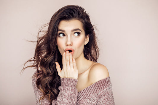 woman in sweater with hand to her mouth in surprise